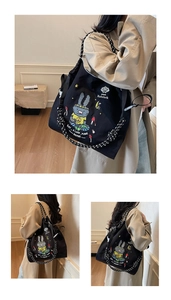 Detail of black canvas tote bag showing cartoon rabbit embroidery and polka dot straps