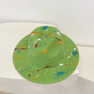 Detailed top view of light green straw hat featuring colorful artistic paint splatters