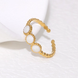 Gold adjustable stainless steel ring with three oval white gemstones on a white surface