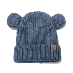 Detail of blue knitted baby hat with bear ears and maple leaf leather patch texture