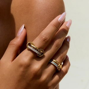 Close-up of layered gold zircon rings with micro-pave crystals on model's hand