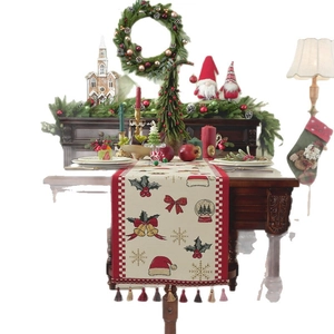 Christmas table runner with red snowflakes and tassels on a cozy festive dining table