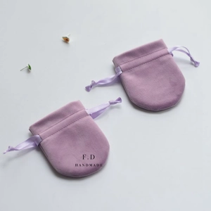 Close-up of purple velvet drawstring jewelry pouches with ribbon ties and F.D print