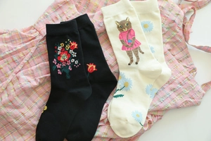 Detail of floral embroidery and cat pattern on cotton crew socks in black and cream