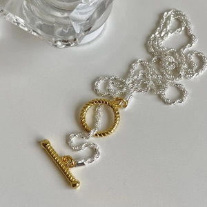 Two-tone silver twist rope chain necklace with golden OT toggle clasp on white background