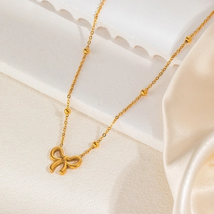 Close-up of golden butterfly necklace on champagne silk and white geometric steps