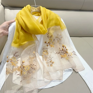 Detail of elegant floral embroidery on yellow and beige blended silk scarf fabric