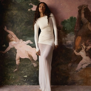 Close-up of white slim fit backless dress with ruched details and glossy fabric finish