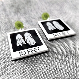 Close-up of acrylic Halloween earrings featuring ghost print and 'NO FEET' text design
