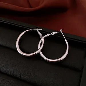 Polished silver hoop earrings with a minimalist design on an elegant dark texture