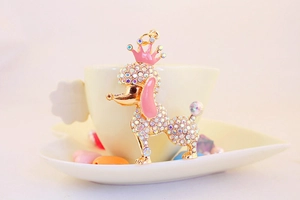 Close-up of golden poodle keychain with pink crown and sparkling rhinestone details