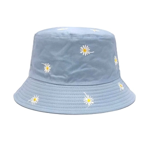 Detailed close-up of daisy flower embroidery on light blue cotton sun hat fabric