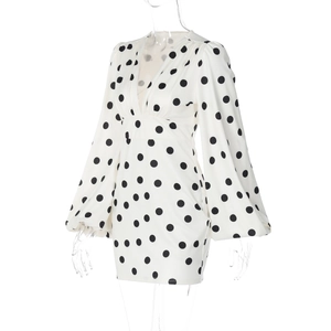 Dettaglio dell'abito bianco a pois con profondo scollo a V e maniche a sbuffo alla moda