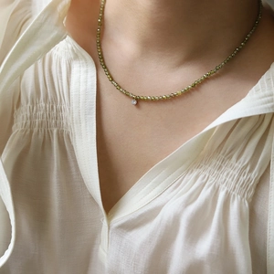 Detailed close-up of olive green beaded necklace with a central zircon pendant