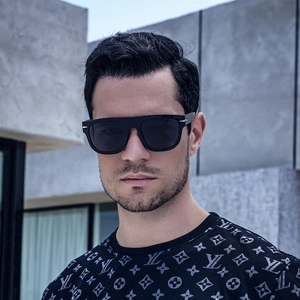 Close-up of black thick-frame oversized square sunglasses worn by a male model