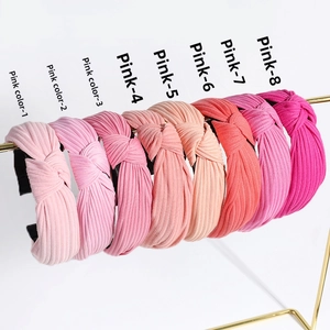 Row of eight knotted ribbed headbands in a gradient of pink shades on a gold stand