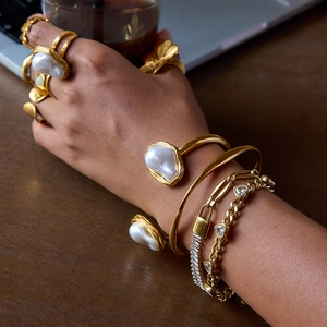 Gros plan d'un ensemble bracelet et bague en acier doré avec perles baroques et zircon
