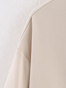 Close-up of beige bomber jacket shoulder showing fine twill fabric and seam detail