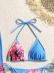 Detailed close-up of blue bikini with pink floral print on a summer beach woven mat