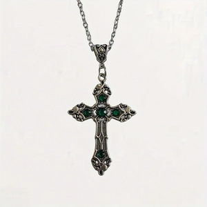 Detail of vintage silver cross necklace featuring intricate engravings and green gemstones