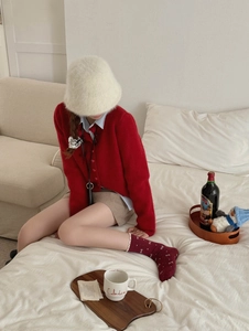Detail of red festive crew socks with white bow pattern styled with knit cardigan