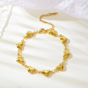 Close-up of golden heart link bracelet with extension chain on white background