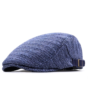 Detail of blue herringbone straw newsboy cap featuring side buckle and bronze fastener