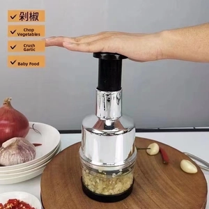 Action shot of manual garlic press mincing chili and vegetables on a wooden board