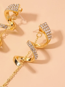 Gros plan de boucles d'oreilles spirales dorées avec strass et pampilles à chaînes