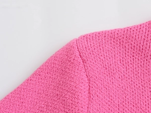 Detail of pink knit cardigan showing high-quality shoulder stitching and fabric texture