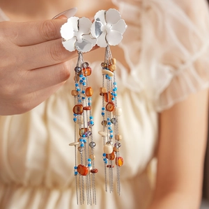 Detail of silver floral stud with colorful beaded tassels and bohemian metal chains