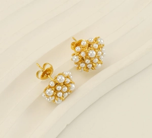 Close-up of vintage 18k gold plated pearl stud earrings with textured sunflower design