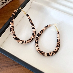 Detailed view of leopard print woven hoop earrings displayed in a black jewelry box