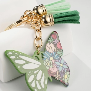 Colorful butterfly keychain with green tassels and gold hardware on white background