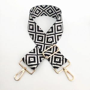 Detail of adjustable black and white geometric wide bag strap with gold metal hooks