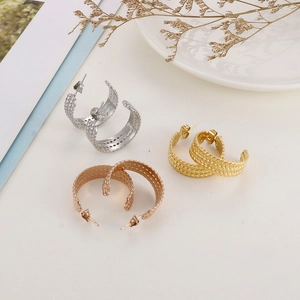 Detailed view of C-shape titanium earrings with woven texture in gold and silver finish