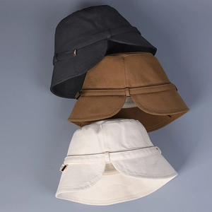 Detailed stack of cotton bucket hats in black, tan, and beige showing fabric texture