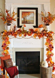 Artificial maple leaf garland decorated on a white fireplace for warm autumn home decor