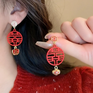 Close-up of red and gold Chinese New Year earrings featuring Fu and Xi characters