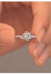 Macro shot of a floral-shaped diamond ring featuring a round center stone on a hand