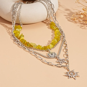 Bohemian multi-layer necklace with sun and star pendants on a ceramic display