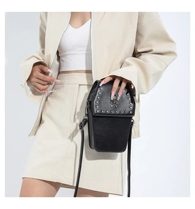 Detailed view of black coffin shaped bag with silver rivets and skull on crossbody model