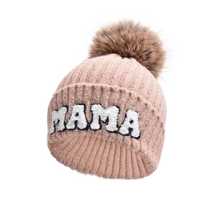 Dettaglio berretto in maglia rosa con ricamo MAMA e pompon di pelliccia sintetica