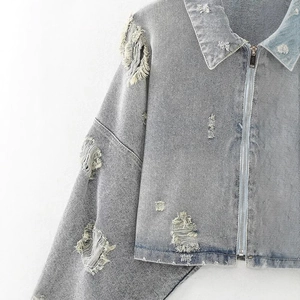 Stylish light blue distressed denim jacket with ripped details and zipper closure