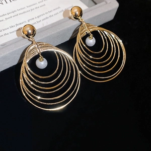 Detail of gold multi-layer circular hoop earrings with pearls on a jewelry display tray