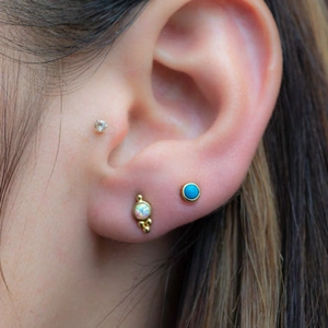 Close-up of S925 silver turquoise flower and opal studs worn on an ear model