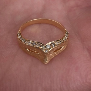 Detail of a matte gold V-shaped ring with small diamonds on a finger close-up