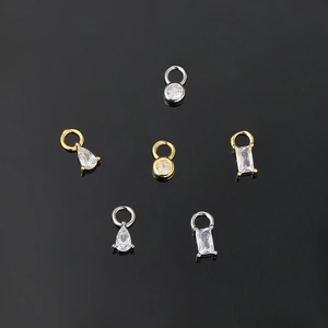 Macro shot of gold and silver charms with various gemstone cuts on a dark surface