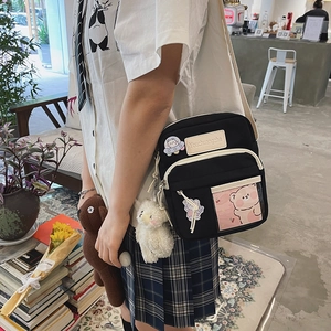 Détail d'un sac bandoulière en toile noire avec écusson d'ours mignon et porte-clés en peluche