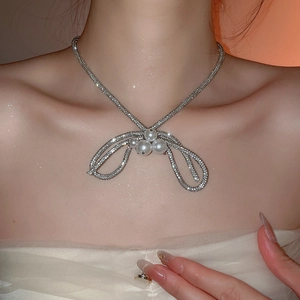 Close-up of elegant silver bow necklace with diamonds and four pearls on female model